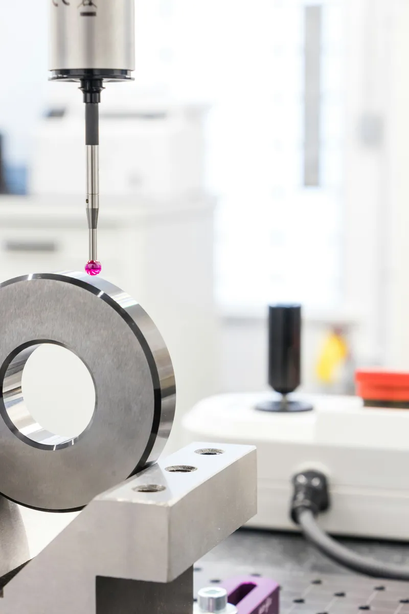 Coordinate measuring machine probe inspecting a precision metal ring